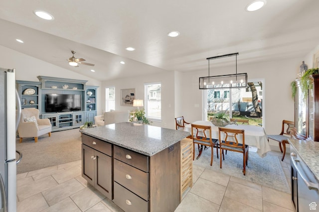 kitchen with light stone countertops, ceiling fan, a kitchen island, lofted ceiling, and freestanding refrigerator