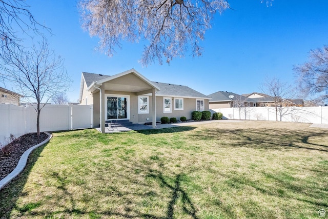 back of house featuring a fenced backyard, a lawn, stucco siding, and a patio