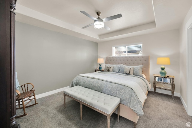 carpeted bedroom featuring baseboards, a tray ceiling, and ceiling fan