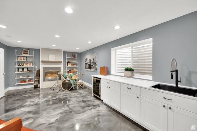 kitchen featuring white cabinetry, recessed lighting, a sink, beverage cooler, and a fireplace