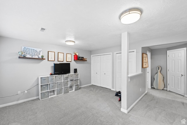basement with baseboards, visible vents, carpet, and a textured ceiling