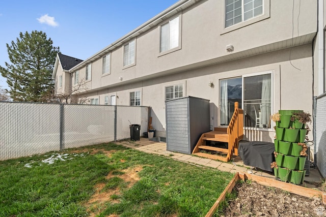 back of property with a fenced backyard, a lawn, and stucco siding