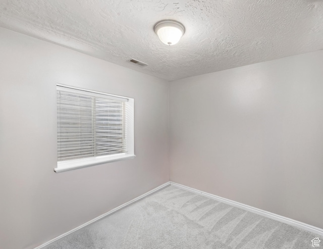 empty room with baseboards, visible vents, carpet flooring, and a textured ceiling