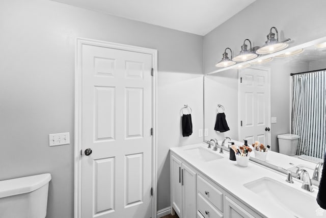 bathroom with double vanity, a sink, and toilet