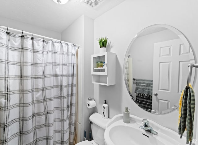 bathroom with visible vents, toilet, a sink, and a shower with shower curtain