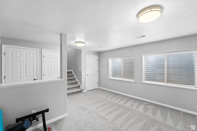 interior space with baseboards, carpet floors, visible vents, and stairway