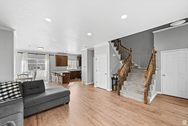 living room with stairway, light wood-style flooring, baseboards, ornamental molding, and recessed lighting
