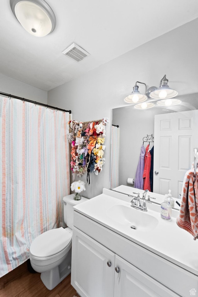 full bathroom with visible vents, toilet, vanity, and wood finished floors