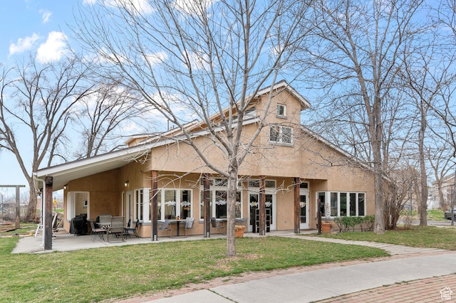 view of front facade featuring a front lawn, stucco siding, and a patio