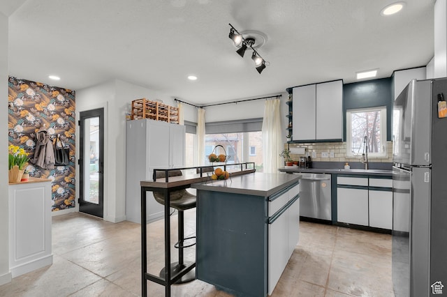 kitchen featuring a kitchen bar, tasteful backsplash, stainless steel appliances, a center island, and a sink