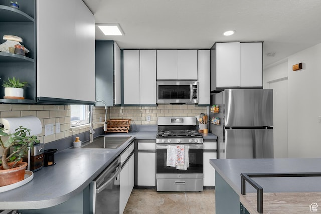 kitchen featuring white cabinets, tasteful backsplash, appliances with stainless steel finishes, a sink, and open shelves