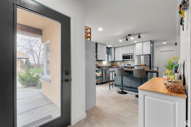 kitchen with white cabinetry, a kitchen bar, appliances with stainless steel finishes, decorative backsplash, and recessed lighting