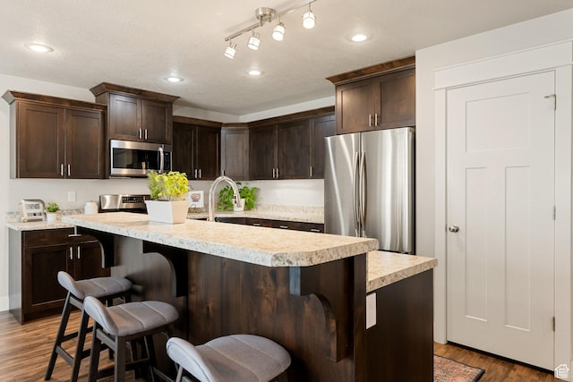 259 W 40 N, Hyrum, UT 84319 - kitchen with stainless steel appliances, dark brown cabinetry, light countertops, a kitchen bar, and recessed lighting