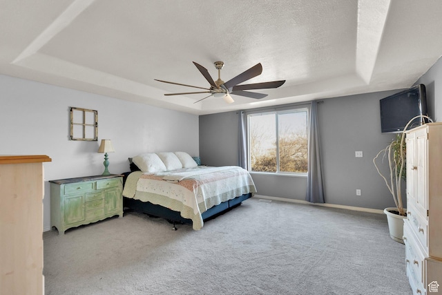 bedroom featuring a raised ceiling, light carpet, baseboards, and a ceiling fan