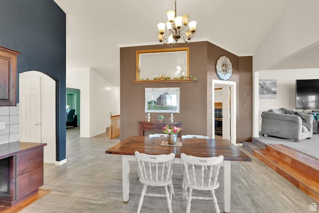 dining area featuring a chandelier, arched walkways, high vaulted ceiling, and baseboards