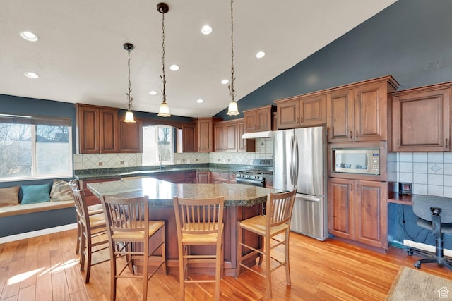 kitchen with a breakfast bar area, a center island, appliances with stainless steel finishes, and decorative backsplash