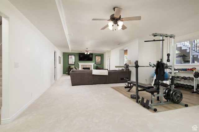 exercise room featuring carpet floors, a tile fireplace, baseboards, and ceiling fan