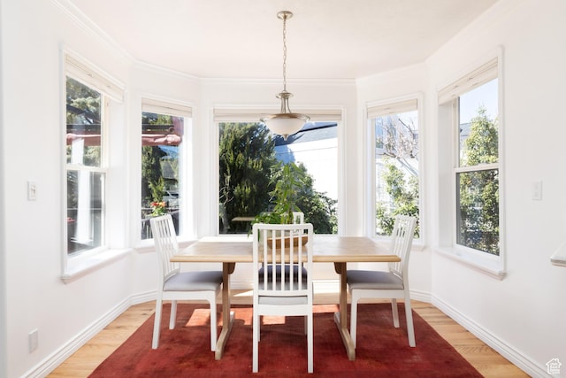 dining area with baseboards, ornamental molding, and light wood finished floors