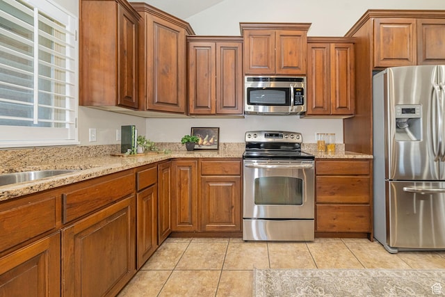 1886 S 830 W Unit D, Syracuse, UT 84075 - kitchen featuring brown cabinets, light stone countertops, appliances with stainless steel finishes, and light tile patterned floors