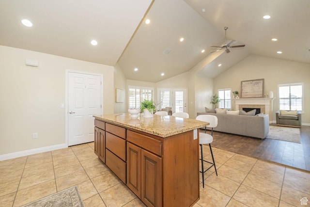 1886 S 830 W Unit D, Syracuse, UT 84075 - kitchen featuring a ceiling fan, a kitchen island, light stone counters, a breakfast bar area, and brown cabinetry