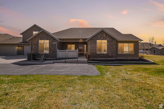 ranch-style home with stone siding, concrete driveway, a garage, a lawn, and a porch
