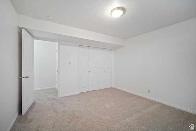 unfurnished bedroom with baseboards, carpet floors, a textured ceiling, and a closet
