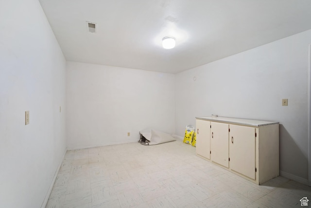 spare room featuring baseboards and light floors