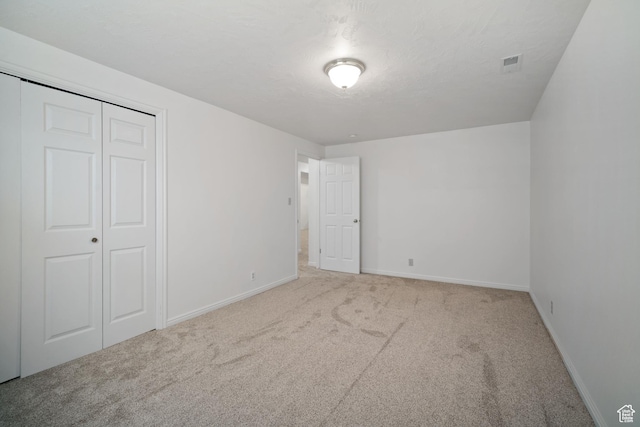 unfurnished bedroom with a closet, a textured ceiling, visible vents, baseboards, and carpet floors