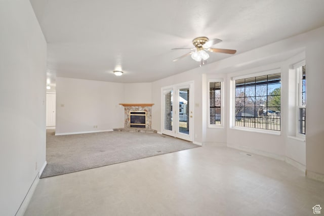 unfurnished living room with a fireplace, ceiling fan, and baseboards