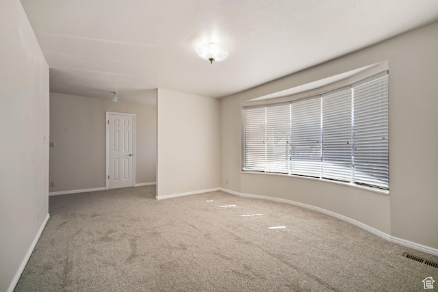 empty room featuring carpet, baseboards, and visible vents
