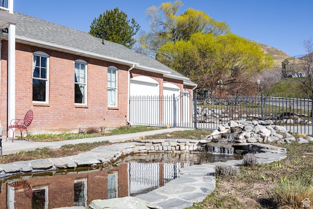 67 E Dorchester Dr, Salt Lake City, UT 84103 - view of side of home featuring a shingled roof, an attached garage, fence, and brick siding