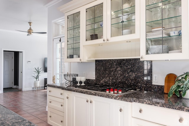 67 E Dorchester Dr, Salt Lake City, UT 84103 - kitchen with decorative backsplash, tile patterned floors, stainless steel gas stovetop, a ceiling fan, and glass insert cabinets