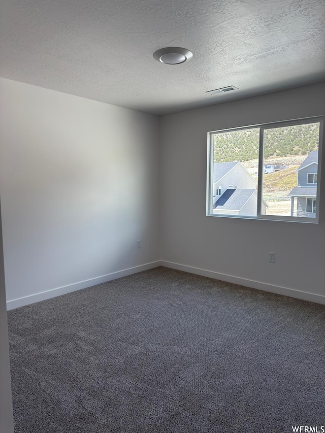 7326 N Long Ridge Dr Unit 614, Eagle Mountain, UT 84005 - empty room featuring a textured ceiling, dark colored carpet, and baseboards