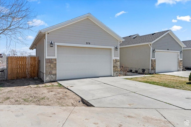 379 S Utah Dr, Grantsville, UT 84029 - view of front facade with stone siding, driveway, fence, and an attached garage