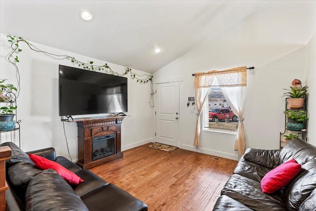 379 S Utah Dr, Grantsville, UT 84029 - living room featuring vaulted ceiling, baseboards, light wood finished floors, visible vents, and a glass covered fireplace