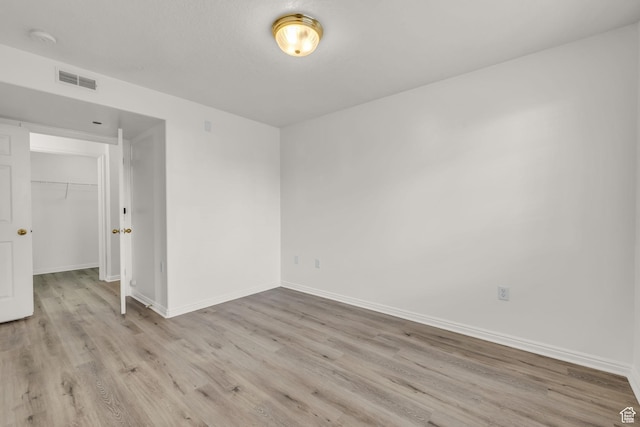 empty room with wood finished floors, baseboards, and visible vents