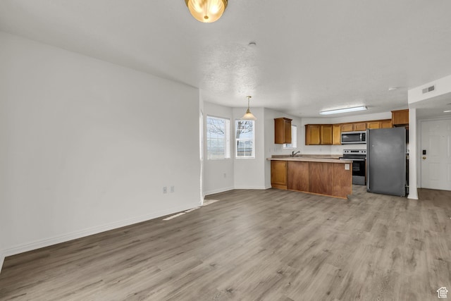 kitchen featuring a peninsula, brown cabinets, stainless steel appliances, light wood-type flooring, and open floor plan