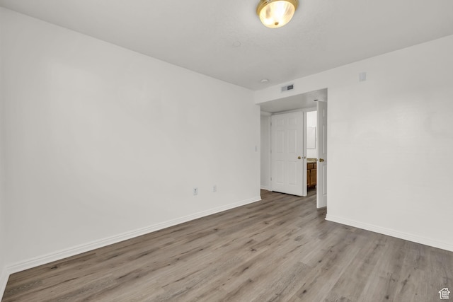unfurnished room featuring baseboards, visible vents, and wood finished floors