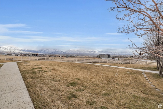 view of yard with a rural view, fence, and a mountain view