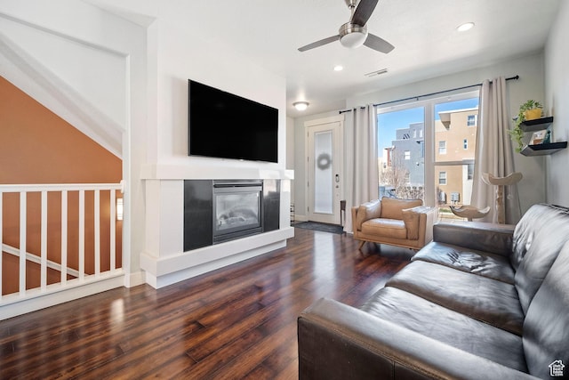 living area with wood finished floors, a glass covered fireplace, visible vents, ceiling fan, and recessed lighting