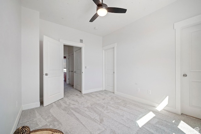 unfurnished bedroom featuring a ceiling fan, light carpet, baseboards, and visible vents
