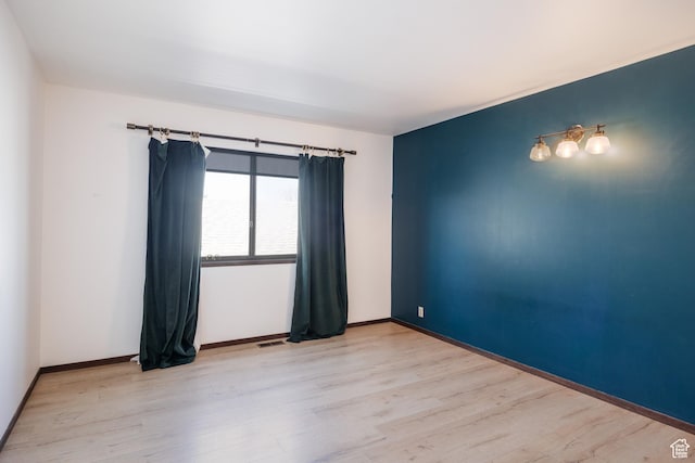 spare room with visible vents, baseboards, and light wood-type flooring