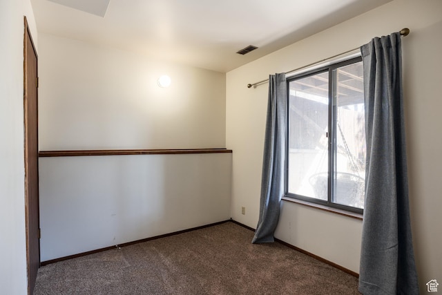 carpeted empty room featuring baseboards and visible vents