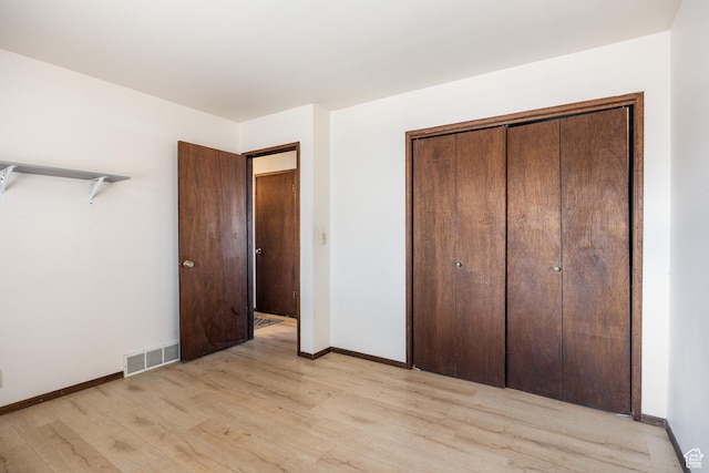 unfurnished bedroom featuring baseboards, visible vents, a closet, and light wood-style floors
