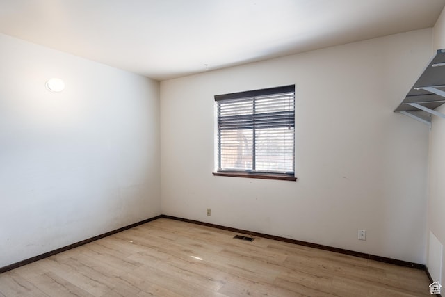 unfurnished room with baseboards, visible vents, and wood finished floors