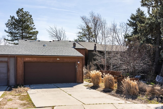 view of front of property featuring a garage, concrete driveway, and a shingled roof