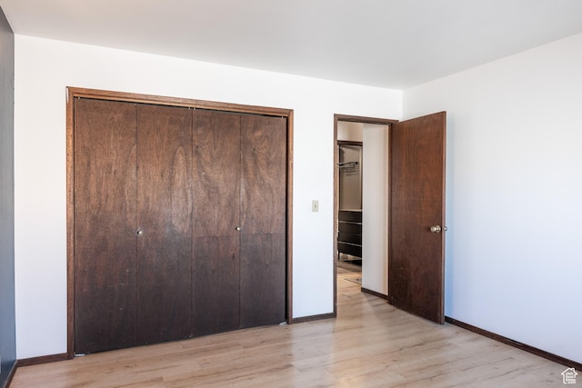 unfurnished bedroom with a closet, baseboards, and light wood-type flooring