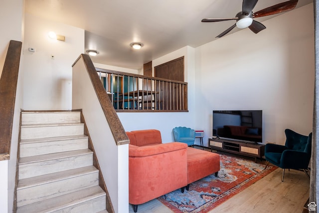 living room with wood finished floors, stairway, and a ceiling fan