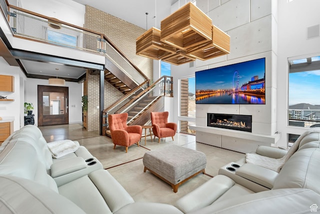 4601 N Toscana Hills Dr, Lehi, UT 84043 - living area with finished concrete flooring, visible vents, stairs, a glass covered fireplace, and a high ceiling