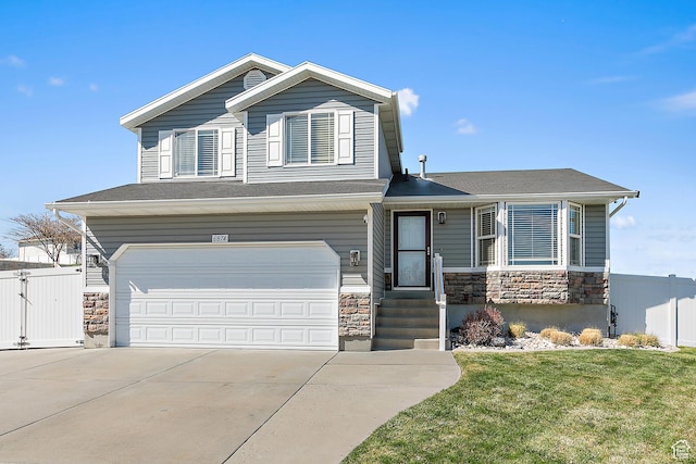 6874 S Hoyle Cir, West Jordan, UT 84081 - split level home with concrete driveway, fence, an attached garage, stone siding, and a front yard